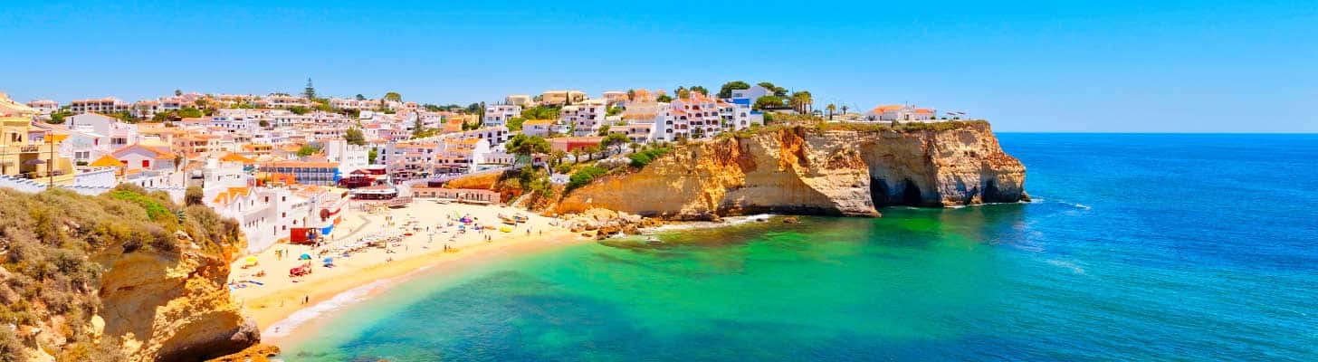 Houses perched on the cliff top overlooking a beach in the Algarve