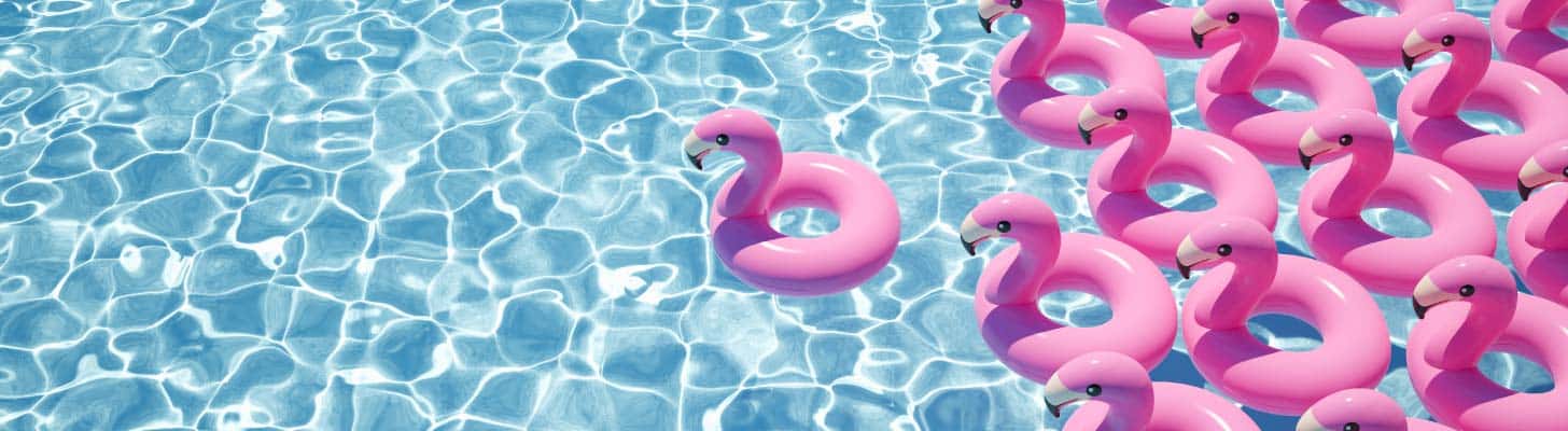 Pink inflatable flamingoes floating on clear blue water